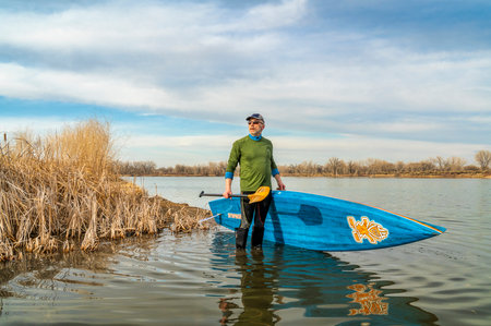 Fort Collins, CO, USA - March 12, 2019: Early spring stand up paddling, senior male launching his...