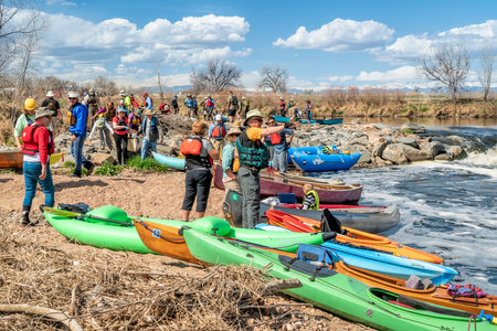 Brighton, CO, USA - April 6, 2019 : A diversified group of paddlers during annual trip on the South Platte River below Denver - portaging kayaks, canoes and rafts over a rapid.のeditorial素材