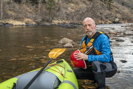 environmental portrait of a senior paddler in life jacket with a whitewater inflatable kayak - Poudre River, Colorado in early springの写真素材