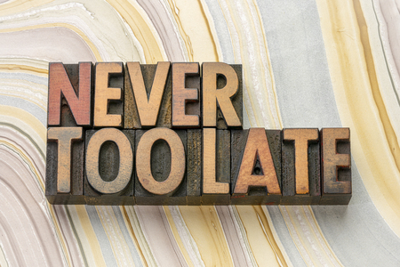 never too late word abstract in vintage letterpress wood type printing blocks against marbled paperの写真素材