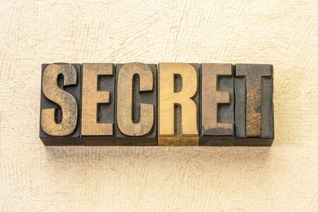 secret word abstract in vintage letterpress wood type against textured handmade paperの写真素材