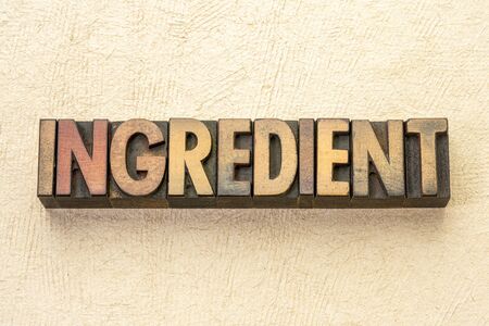 ingredient word abstract in vintage letterpress wood type against textured handmade paperの写真素材
