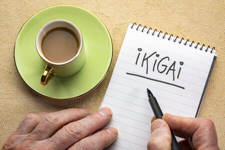 ikigai, a reason for being - man hand writing a note with a black marker in a spiral notebookの写真素材