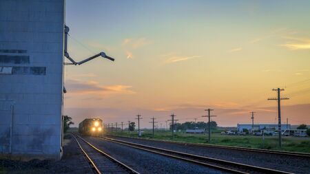 Freight train is approaching a rural town in Nebraska at dusk.の写真素材