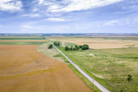 aerial view of rural Nebraska landscape with a farm road, wheat fields and hay bales