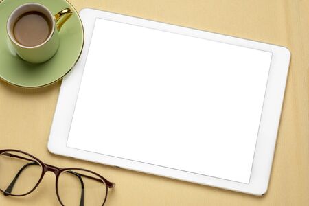 digital tablet with white blank screen, cup of coffee, reading glasses - flat lay concept