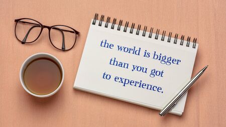 the world is bigger than you got to experience - inspirational quote in a sketchbook with a cup of teaの写真素材