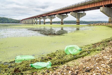 plastic bottle trash on river shore - Tennessee River with John Coffee Memorial Bridge (Natchez...