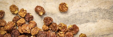 dried goldenberries on a textured bark paper background, panoramic banner