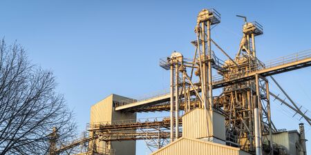 industrial panorama abstract - top of a grain elevator with gravity flow pipes against blue sky