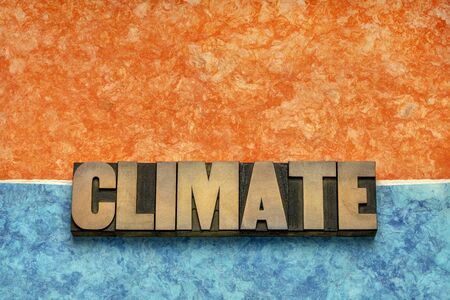 climate word in vintage letterpress wood type against blue and orange handmade textured amate paper, global warming, change and environment conceptの写真素材