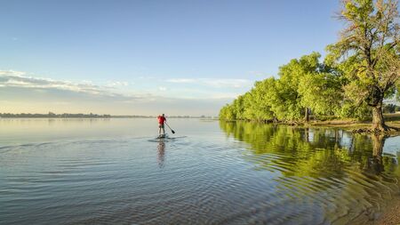 paddling stand up paddleboard on a lake in summer - Boyd Lake State Park in northern Coloradoの写真素材