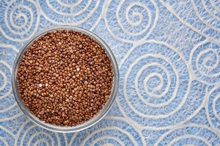 gluten free red quinoa grain in a bowl against lace paper with spiral pattern, healthy eating conceptの写真素材