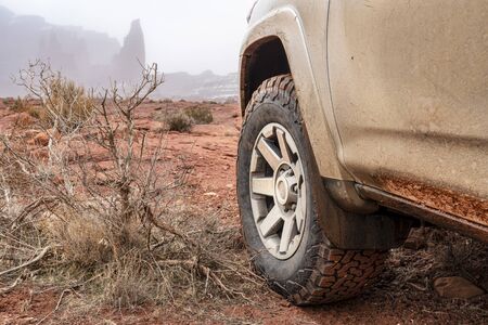 4x4 SUV car or truck driving on a trail in winter conditions - Fisher Towers in Moab area, Utah,...