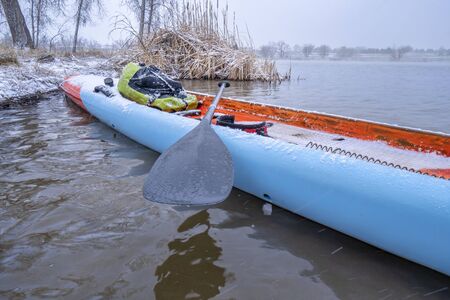 stand up paddleboard in snow blizzard on a lake in northern Colorado, training, fitness and recreation conceptの写真素材