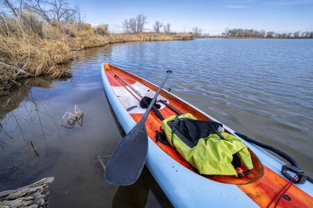 stand up paddleboard with a paddle and dry bag on a lake in northern Colorado, training, fitness and...