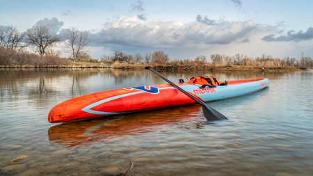 Fort Collins, CO, USA - March 13, 2020: A long racing flatwater stand up paddleboard (Mistral Stealth) on a calm lake after paddling workout in early spring - recreation, training and fitness concept.のeditorial素材