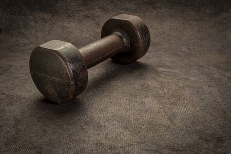 old rusty dumbbell on textured handmade bark paper with a copy space, fitness conceptの写真素材