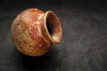 small red and brown clay plant pot (mass produced planter) with rough, grunge finish on dark textured paper backgroundの写真素材