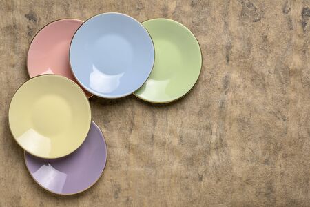 set of empty pastel porcelain saucers against handmade bark paper with a copy spaceの写真素材