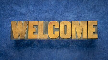 welcome sign - word in vintage letterpress wood type over blue handmade paper, hospitality conceptの写真素材
