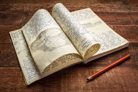 Vintage expedition journal on a rustic picnic table. Travel log from paddling trip across north...