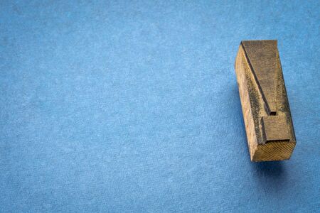 exclamation mark in vintage letterpress wood type against blue handmade paper with a copy space