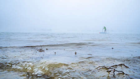 Stand up paddler on a foggy lake - Boyd Lake State Park in northern Colorado, a popular boating and...