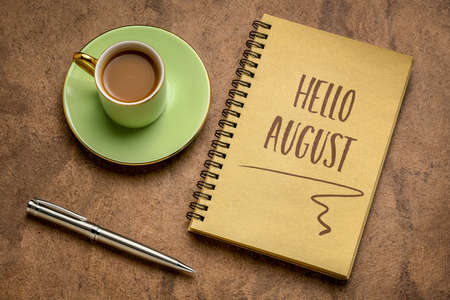 Hello August welcome note  - handwriting in a spiral sketchbook with a cup of coffee, greeting card and calendar conceptの写真素材