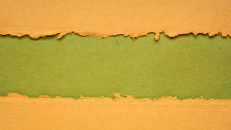 orange and green paper abstract with a copy space - sheets of bark and cotton rag paper, blank web bannerの写真素材