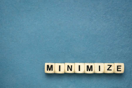 minimize word in wooden cubes against handmade textured rag paper with a copy space, simplicity,...