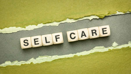 self care word abstract in wooden cube letters on a handmade paper - mental, emotional, and physical health conceptの写真素材