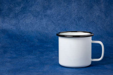 white metal enamel cup of tea on a blue texturted paper background with a copy spaceの写真素材
