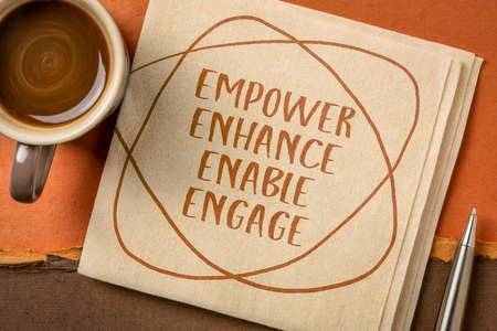 motivational leadership, coaching business or personal development concept - empower, enhance, enable and engage words, handwriting on napkin with a cup of coffeeの写真素材