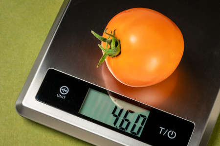 fresh yellow tomato on a digital nutrition diet scale, healthy eating conceptの写真素材