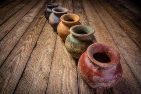 row os small grunge clay pots  with rough color finish on a weathered wood, soft focus image shot with lensless pinhole cameraの写真素材