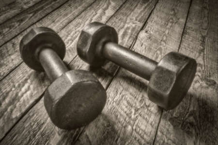 a pair of vintage iron rusty dumbbells on a rustic wood, exercise and fitness concept, soft focus, painterly image shot with a lensless pinhole cameraの写真素材