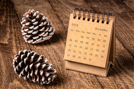 December 2020 - spiral desktop calendar on a rustic wood table with a decorative frosty pine cones, time and business conceptの写真素材