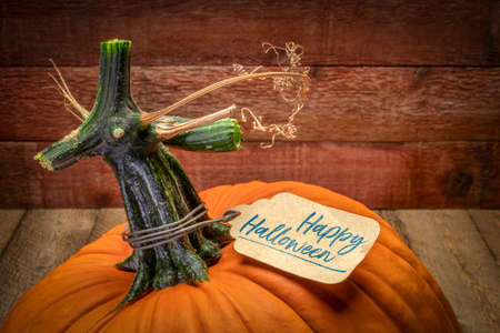Happy Halloween - a pumpkin with a paper price tag against rustic barn wood, fall holiday concept and greeting cardの写真素材
