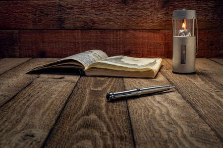 Vintage expedition journal on a rustic picnic table  with a candle lantern - handwriting and drawing...