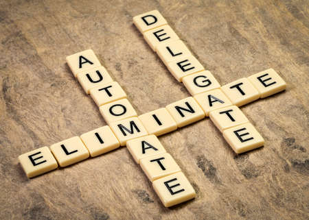 business productivity and lifestyle concept: eliminate, automate and delegate, crossword in ivory letters against textured bark paperの写真素材