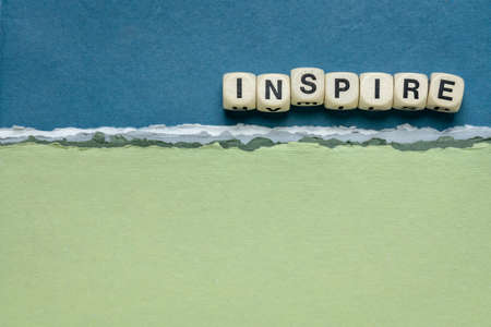 inspire word abstract in wooden letter cubes against handmade paper abstract in blue and green tones, inspiration, leadership and role model conceptの写真素材