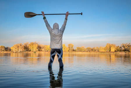 silhouette of a male stand up paddler warming up and stretching, fall scenery of a lake in northern COloradoの写真素材