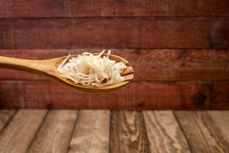 sauerkraut (fermented cabbage) on a wooden spoon against rustic barnwood background, probiotics concept - fermented food good for gut healthの写真素材