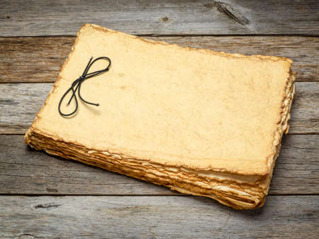 blank retro sketchbook with tan toned heavyweight deckle edge paper sheets on a rustic weathered...