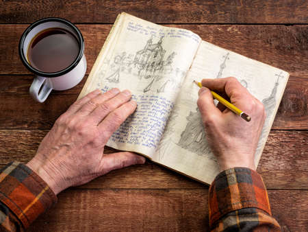 Pencil sketching in a vintage travel journal  (property release attached) on a rustic picnic table...