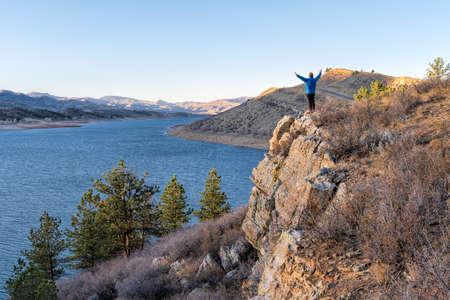 male hiker on a cliff overlooking Horsetooth Reservoir, popular recreation destination for boating, hiking and biking in northern Colorado, fall sceneryの写真素材