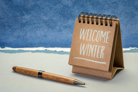 welcome winter greeting card - handwriting in a spiral desktop calendar against abstract paper landscapeの写真素材