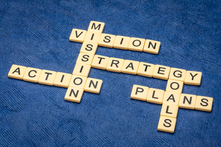 vision, mission, goals, strategy, plan  and action crossword in ivory letter tiles against textured handmade paper, building business conceptの写真素材