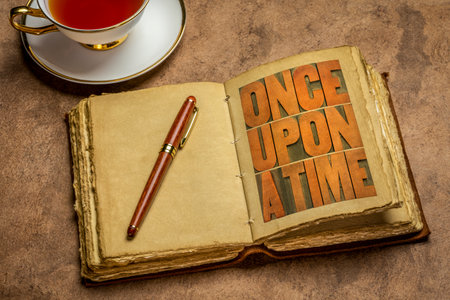 once upon a time opening phrase - storytelling concept - wood type word abstract in a retro journal with a cup of teaの写真素材